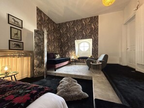 A bedroom with a bed, a sofa, a chair, a small table, and a window. - HENRI II  (Le Mans)