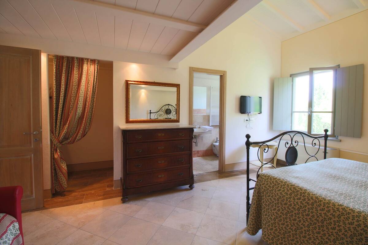 A bedroom with a bed, a dresser, a mirror, and a window.