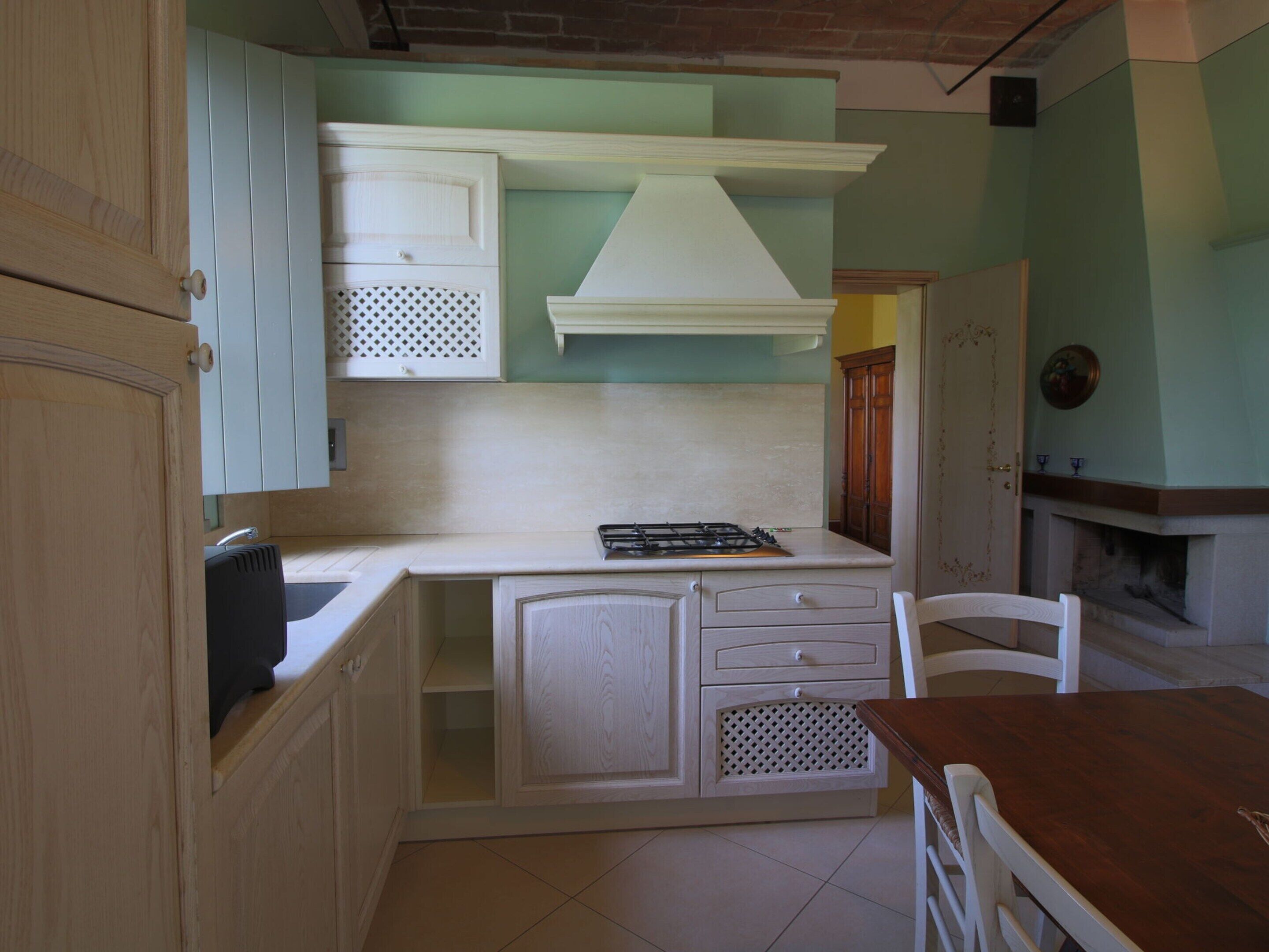 A compact kitchen with white cabinetry, a gas stove, and a dining area with a wooden table and chairs.