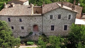 Un bâtiment en pierre avec un toit en tuiles, de nombreuses fenêtres et une arche centrale.