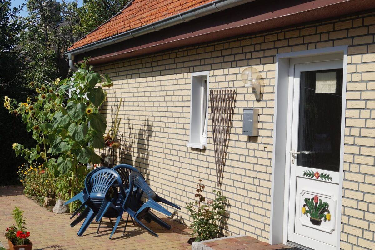Une maison en briques avec une porte blanche, une petite fenêtre et un panneau solaire sur le mur.