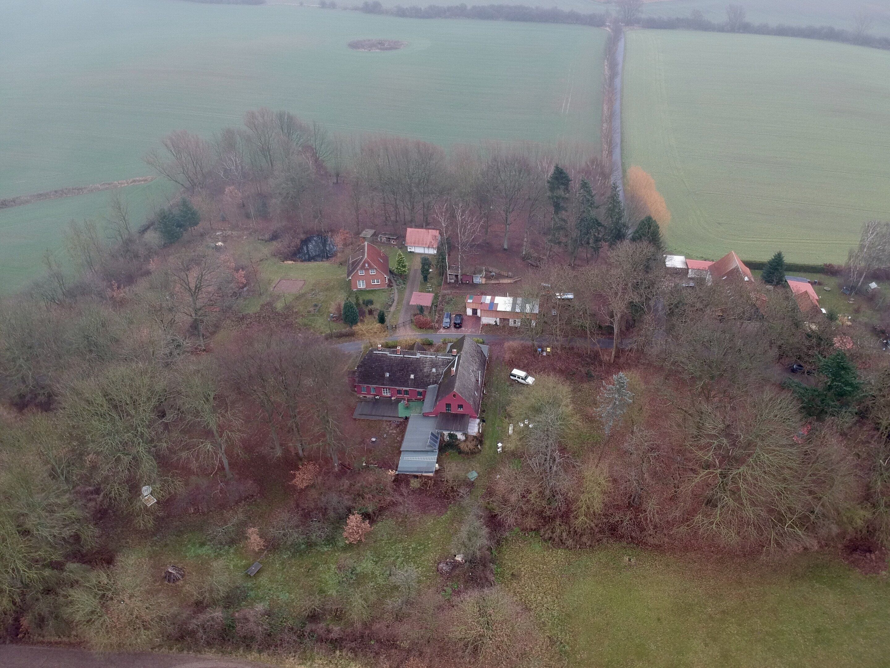 Luchtbeeld van een landelijk gebied met verschillende huizen, een groot veld en een waterpartij.