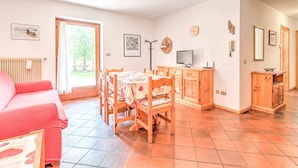 A cozy room with a dining table, chairs, a pink sofa, a wooden cabinet, and a radiator. - Spacious Chalet With Garden Near Ski Area in Tyrol (San Giovanni di Fassa)