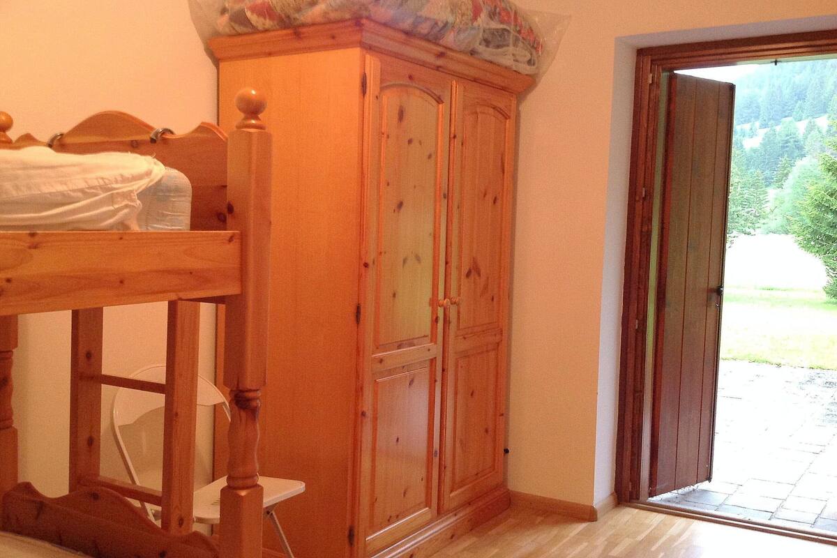 A bedroom with a wooden bed, a wardrobe, and a door leading to a balcony.