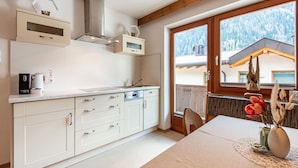 A modern kitchen with white cabinets, a built-in oven, and a window overlooking a snowy mountain.