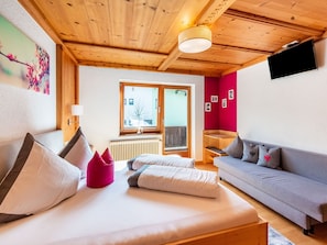 A cozy room with a bed, a sofa, a window, and a wooden ceiling. - Cozy Apartment in the Heart of the Otztal (Umhausen)