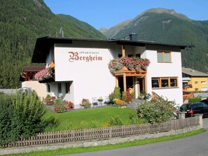 A white building with a sign reading "Appartement Bergheim" and a balcony with flowers. - Cozy Apartment in the Heart of the Otztal (Umhausen)