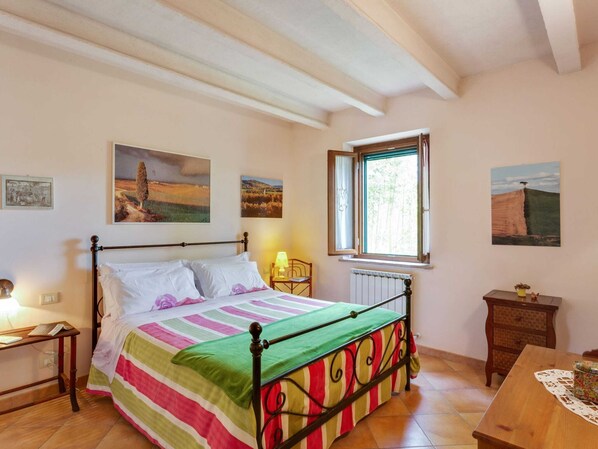 Un dormitorio con una cama, una mesita de noche, una mesa y un ventanal.