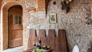 A rustic interior with a stone wall, wooden table, and a sign reading "ARCHI". - Farmhouse in Ville di Corsano Siena at the Centre (Monteroni d'Arbia)