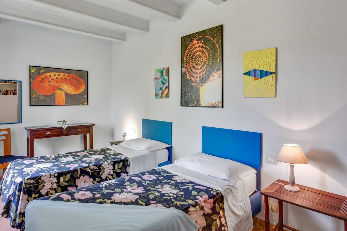 Une chambre avec deux lits, une table de chevet, une lampe et des œuvres d’art accrochées aux murs.
