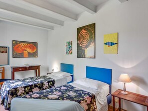 Un dormitorio con dos camas, una mesita de noche, una lámpara y obras de arte en las paredes.