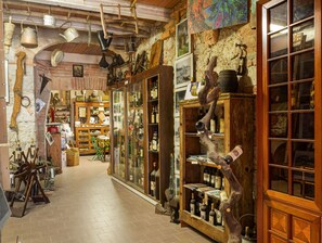 Un pasillo estrecho con decoración rústica, que incluye estanterías de madera y objetos antiguos.