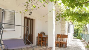 A stone-paved outdoor area with a bench, wooden chairs, and a table. - Countryside Getaway Close to the River and the sea (Omis)