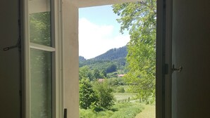 Vista a través de una puerta abierta que revela un paisaje verde exuberante con árboles y colinas al fondo.