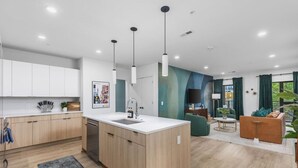 A modern kitchen with a central island, wooden cabinets, and pendant lighting. - Luxury in The Gulch with Patio & Pool- Walk to Broadway (Nashville)