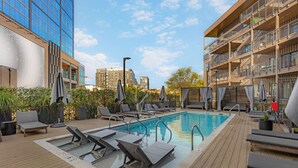 A rooftop pool area with lounge chairs, a pool, and a view of surrounding buildings. - Luxury in The Gulch with Patio & Pool- Walk to Broadway (Nashville)