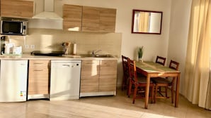 Eine kleine Küche mit Mikrowelle, Toaster und Geschirrspüler, Holzschränken, einer Spüle und einem Essbereich mit Tisch und Stühlen.