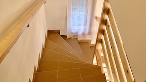 Eine Holztreppe mit Blick auf ein Fenster mit durchscheinenden Vorhängen.