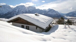 A snow-covered mountain cabin with a wooden exterior and a sloped roof, surrounded by snow-covered mountains and a clear sky. - Chalet in Iselsberg-stronach Near Ski-lift (Iselsberg-Stronach)