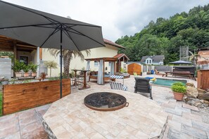 Ein Patio-Bereich mit Grill, Sitzgelegenheiten im Freien und einem Swimmingpool.