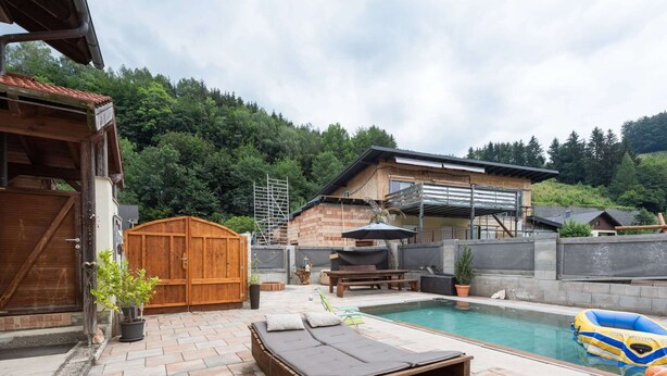 Ein Garten mit Pool, Holzterrasse und Holzzaun.