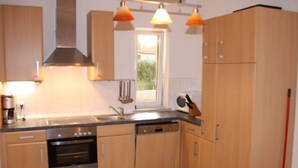 A kitchen with wooden cabinets, a built-in oven, a dishwasher, and pendant lighting. - Splendid Holiday Home in Novigrad Near sea (Novigrad)