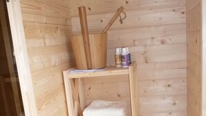 A wooden shelf with a wooden bucket, two bottles, and a folded white towel. - Relaxing Holiday Home in Willersdorf in the Forest (Frankenberg)