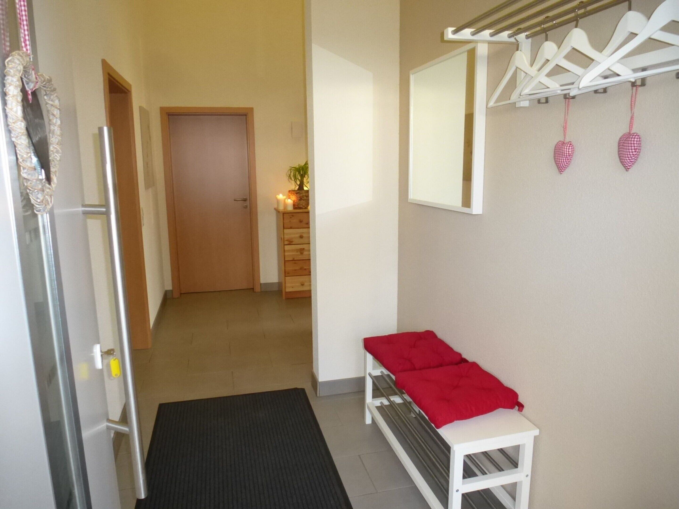 A hallway with a bench, a mirror, and a coat rack with heart-shaped decorations.