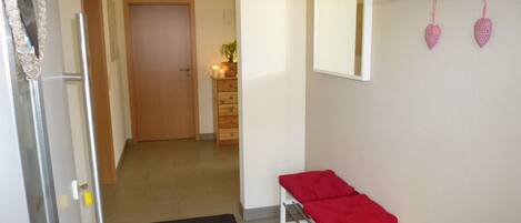 A hallway with a bench, a mirror, and a coat rack with heart-shaped decorations.