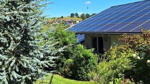 A house with a solar panel roof, surrounded by lush greenery and a well-maintained lawn. - Relaxing Holiday Home in Willersdorf in the Forest (Frankenberg)