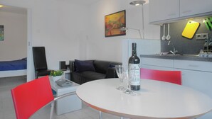 A modern kitchen with white cabinets, a dining table with red chairs, and a bottle of wine on the table. - Holiday Home Near Lawn Bowling in Krabbendam (Warmenhuizen)
