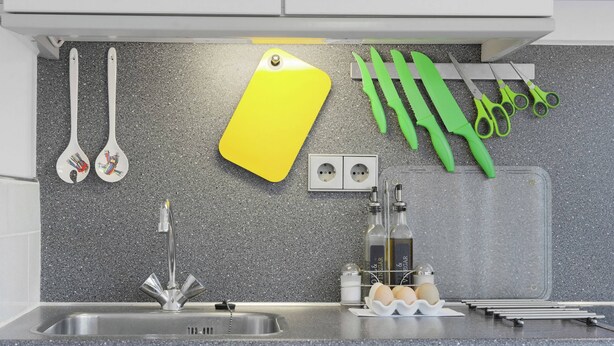 A kitchen with a granite countertop, a stainless steel sink, a yellow cutting board, green scissors, a bottle of vinegar, and a bottle of olive oil. - Holiday Home Near Lawn Bowling in Krabbendam (Warmenhuizen)