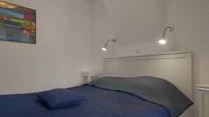 A bedroom with a bed, a nightstand, a wall-mounted lamp, and a painting. - Holiday Home Near Lawn Bowling in Krabbendam (Warmenhuizen)