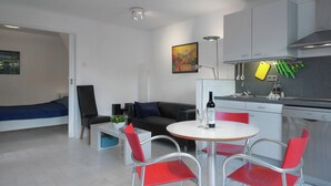 A modern kitchen with a dining area, a bed, and a small table with chairs. - Holiday Home Near Lawn Bowling in Krabbendam (Warmenhuizen)