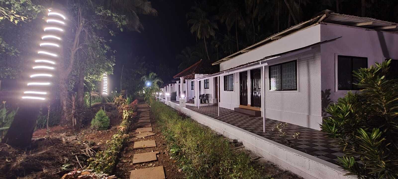 A pathway leading to a row of white buildings with large windows and a paved walkway.