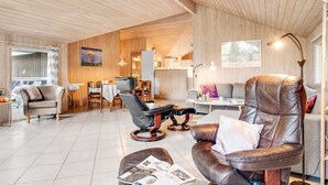 A modern living room with a leather sofa, a dining area, and a kitchen in the background.