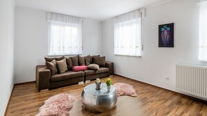 A modern living room with a brown sofa, white curtains, a round coffee table, and a fluffy rug. - Holiday Home in Mahlberg in the Ortenau District (Mahlberg)