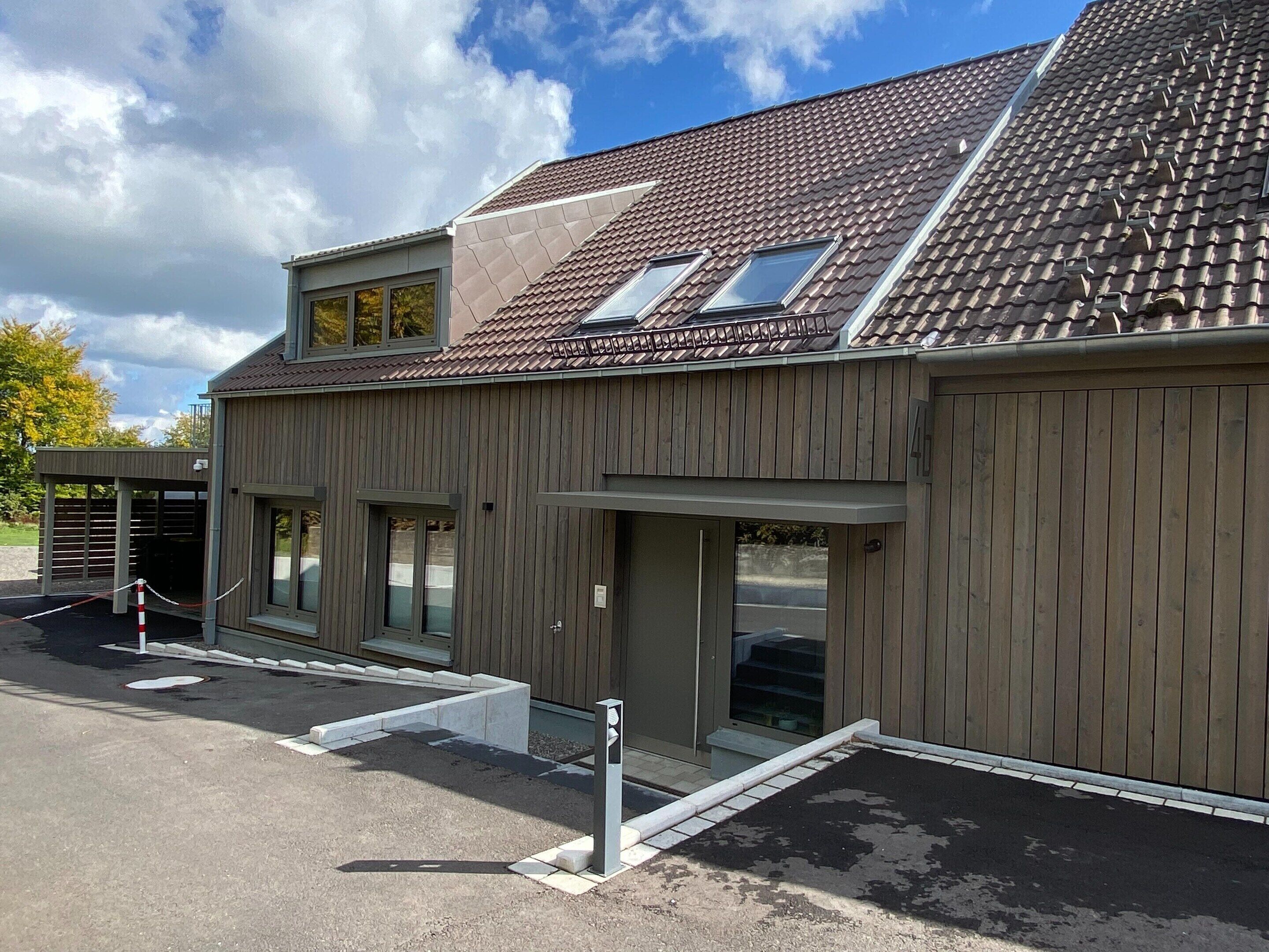 A building with a sloped roof, large windows, and a gated entrance.