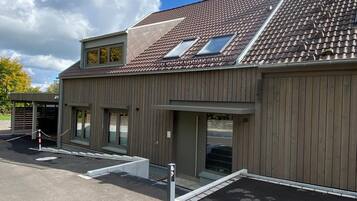 A building with a sloped roof, large windows, and a gated entrance.