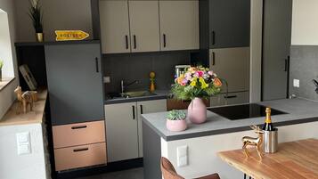 A modern kitchen with grey cabinets, a wooden countertop, and a small dining area with a table and chairs.