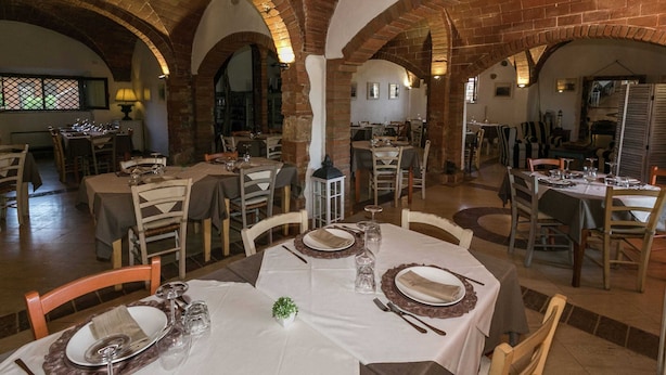 A restaurant with brick arches, white tablecloths, and wooden chairs. - Appealing Apartment Just 7 km From the Beach (Grosseto)