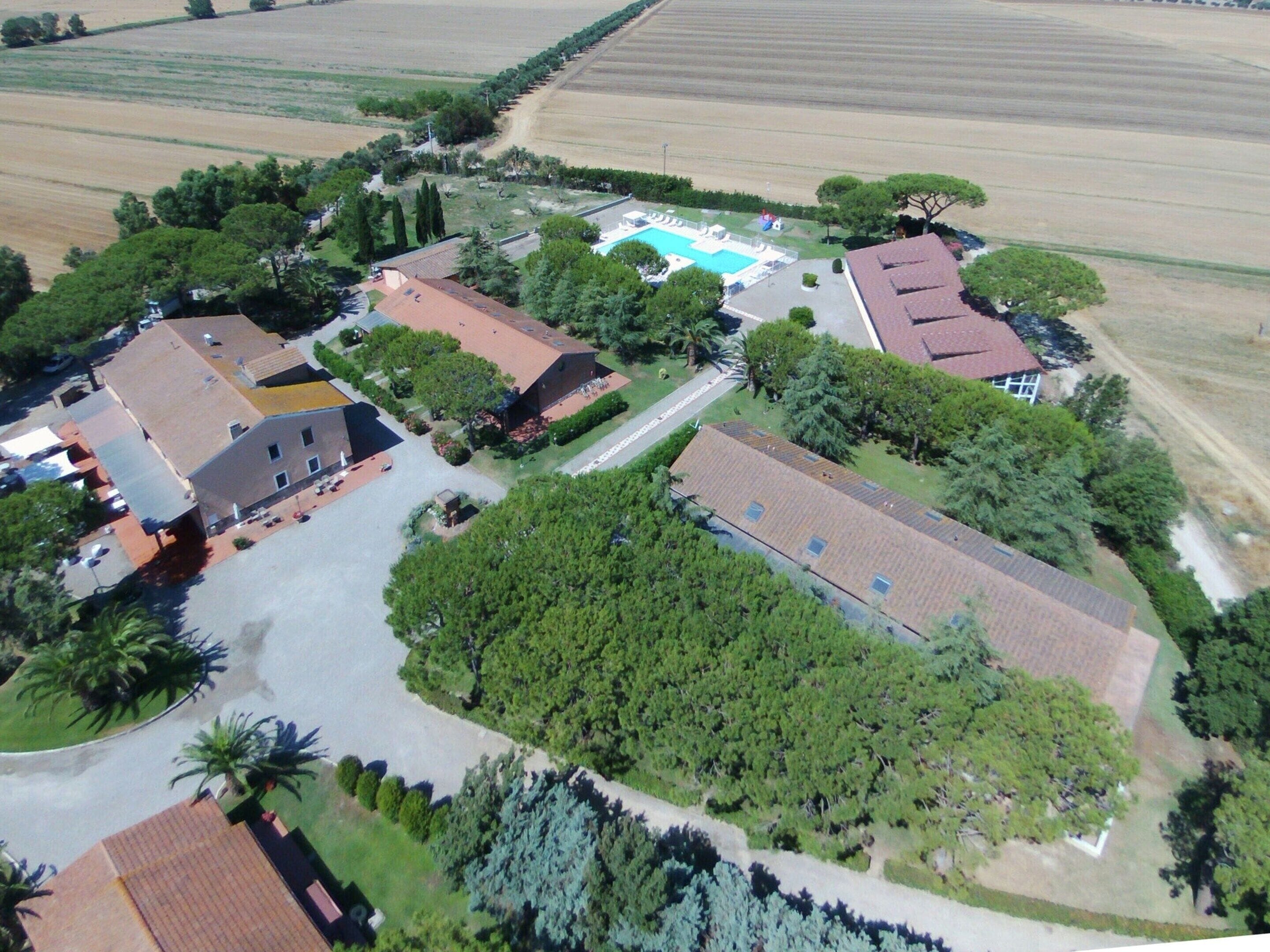 Una vista aerea di una zona residenziale con diverse case, una piscina e campi circostanti.