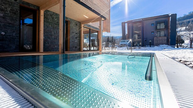Ein modernes Gebäude mit Swimmingpool, Holzterrasse und Bergblick.