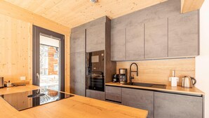 Eine moderne Küche mit Holzausziehtisch, integrierten Geräten und grauen Schränken.