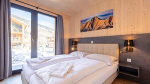Ein Schlafzimmer mit einem großen Bett, zwei Nachttischen, einer Wandlampe und einem Fenster mit Vorhängen.