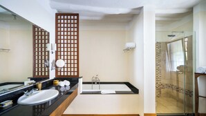 A modern bathroom with a large mirror, a sink, a bathtub, and a glass-enclosed shower.