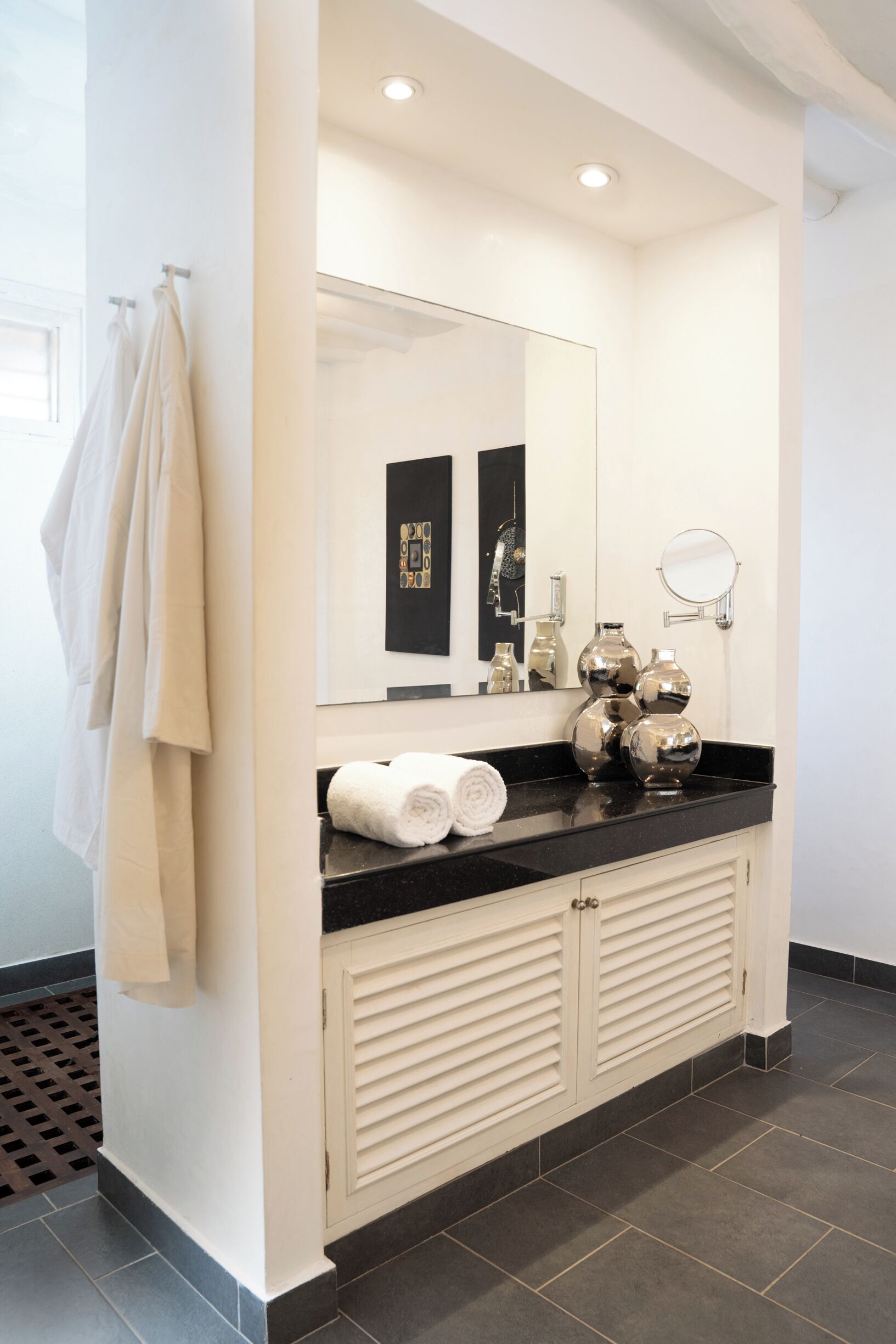 A modern bathroom with a black countertop, two sinks, a large mirror, and a towel rack.