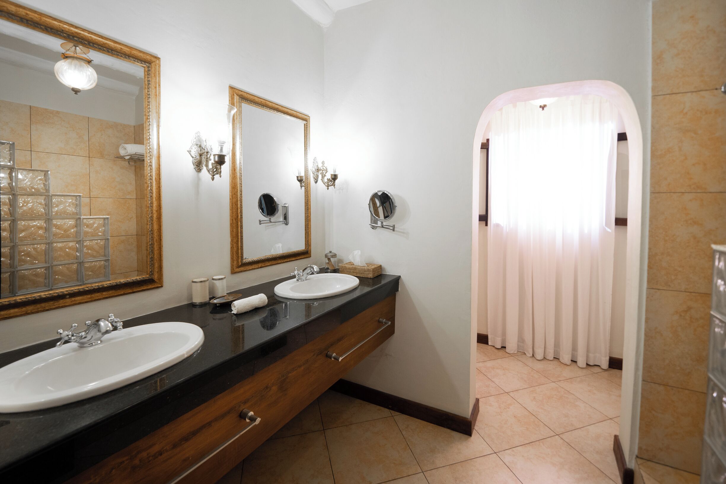 Un baño con dos lavamanos, un espejo grande y un mueble de tocador con cajones.