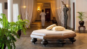 A spacious hotel room with a large bed, a statue, and potted plants.
