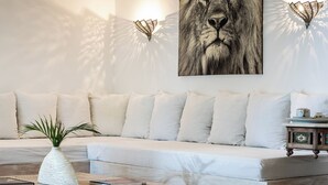 A modern living room with a white sofa, a wooden coffee table, and a large framed artwork of a lion's face. - Lion in the Sun Boutique Hotel & Spa (Malindi)